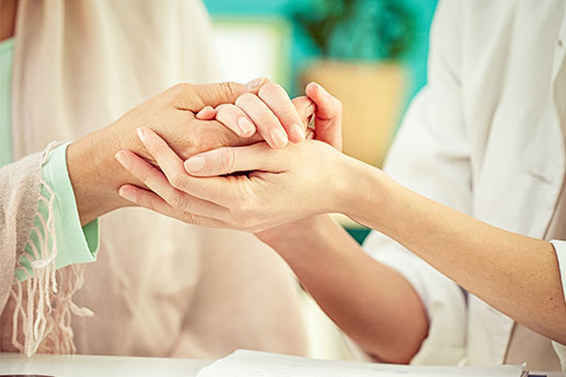 Two women holding hands during in-house counseling session